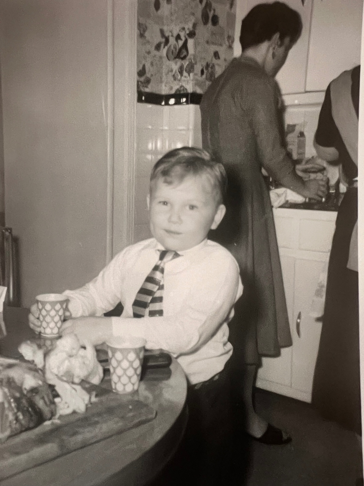 Sunday best in the kitchen — tie on, cup in hand, ready for whatever came next