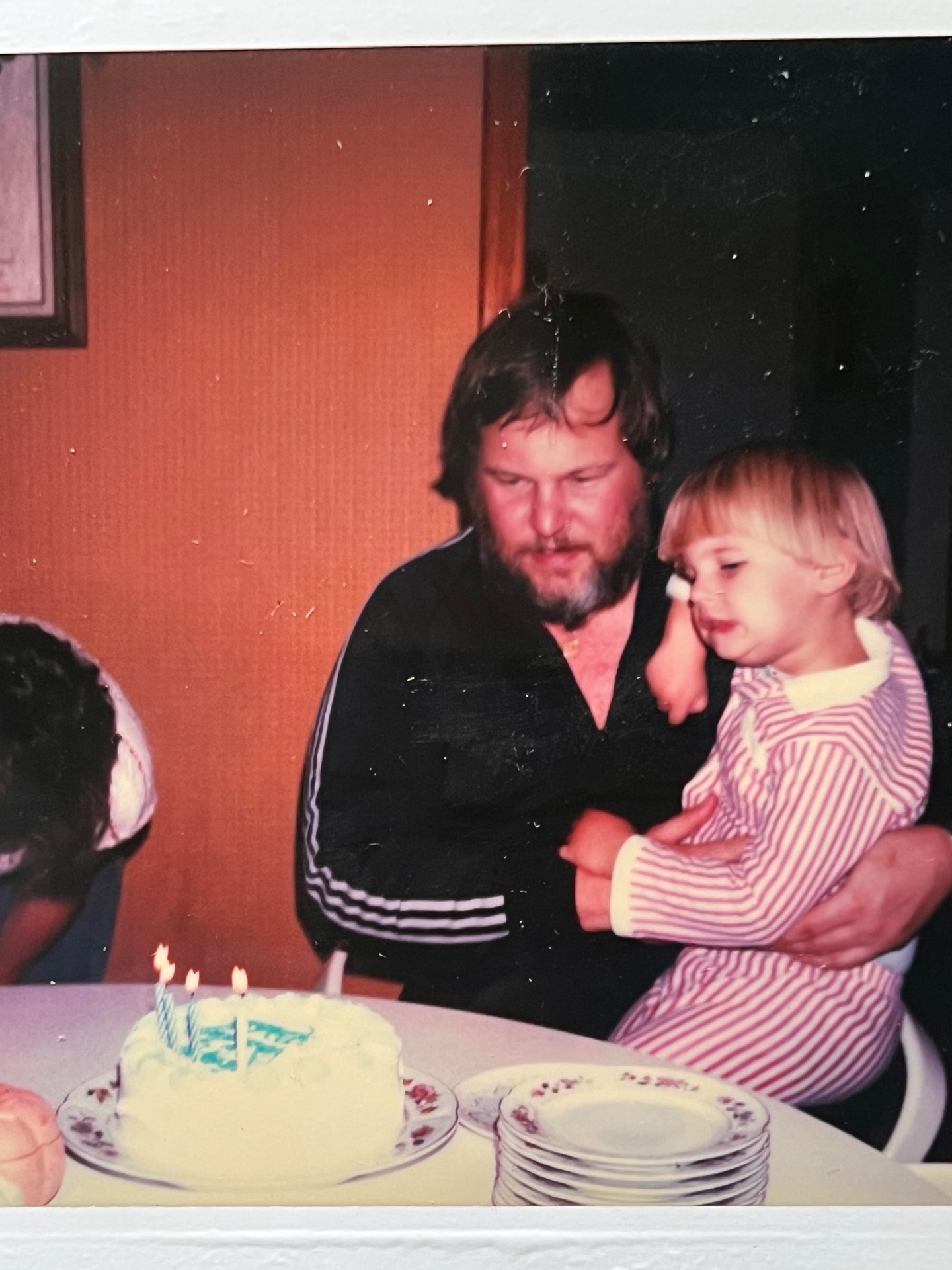 Richard with a little one on his lap — birthday candles glowing