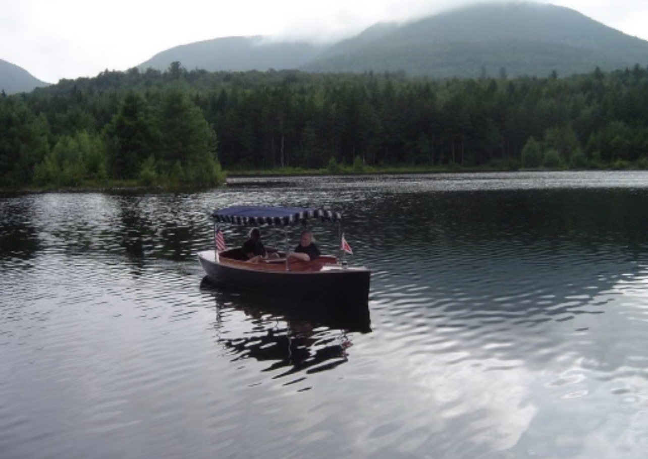 Out on the glassy lake with the mountains behind them — Richard loved this boat and every quiet ride in it