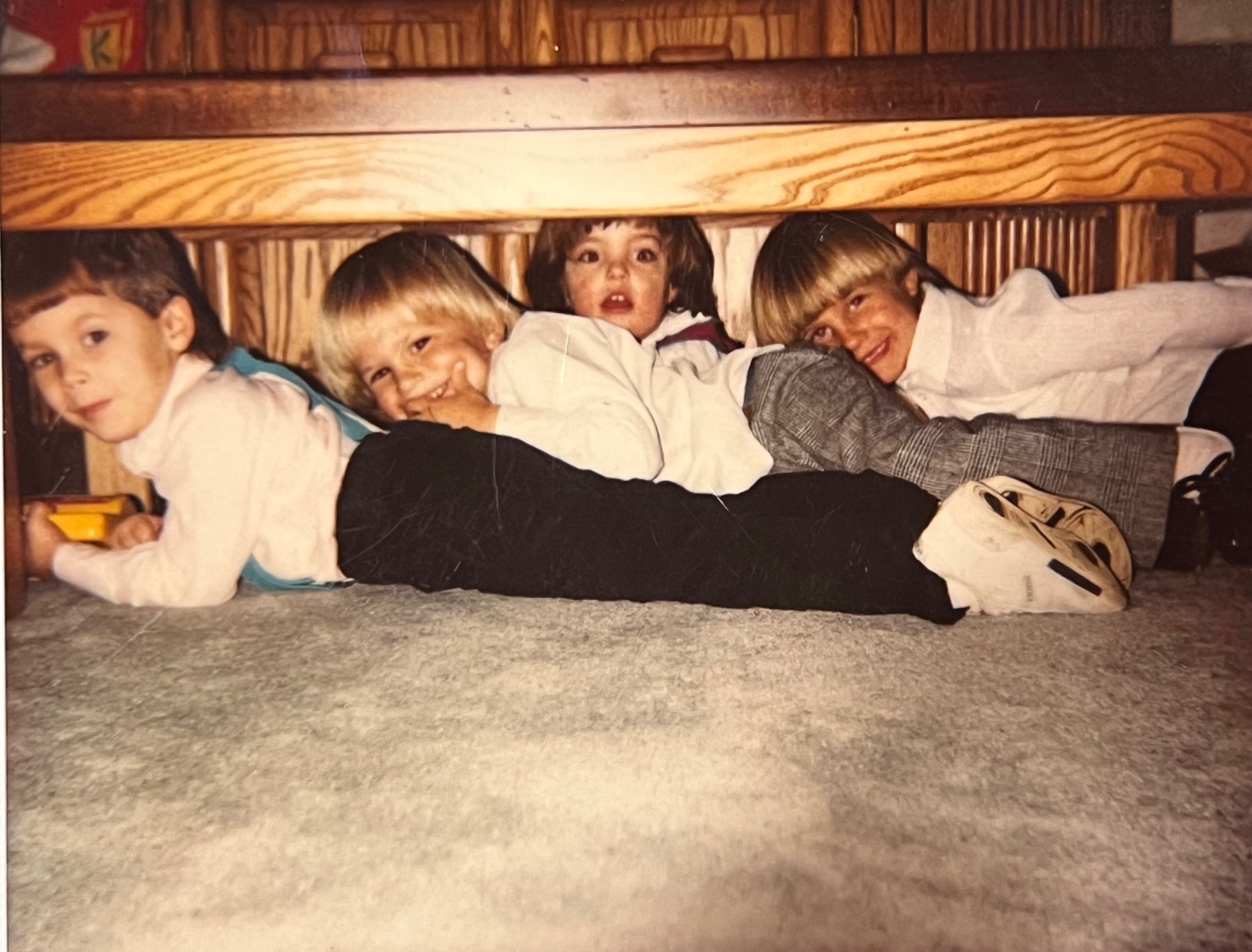 The pack of cousins hiding under the table at The Hideout — pure kid joy, exactly the kind of noise Richard loved