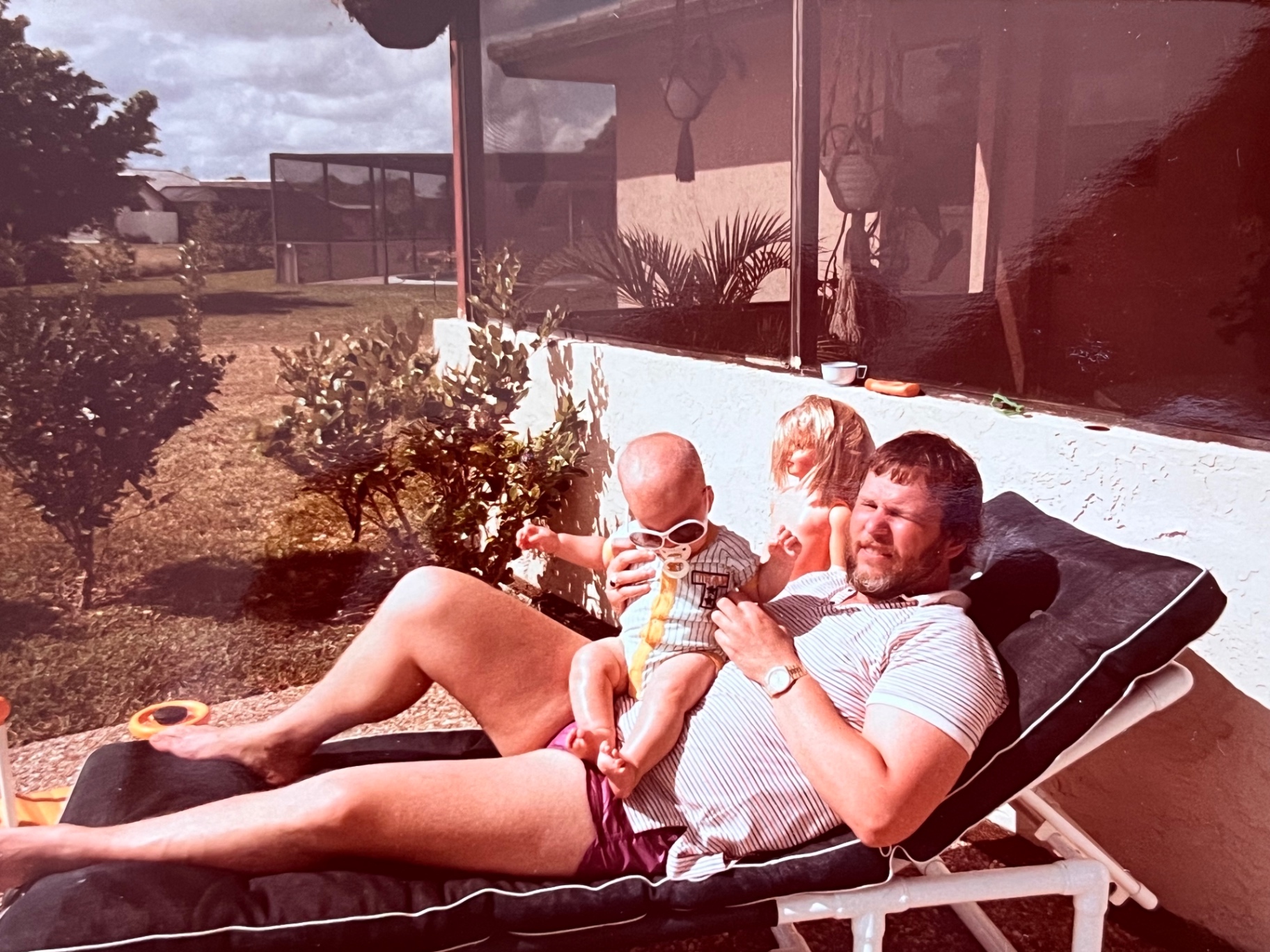 Florida sun, a lounger, and a tiny one in shades — Richard soaking up every second of dad life
