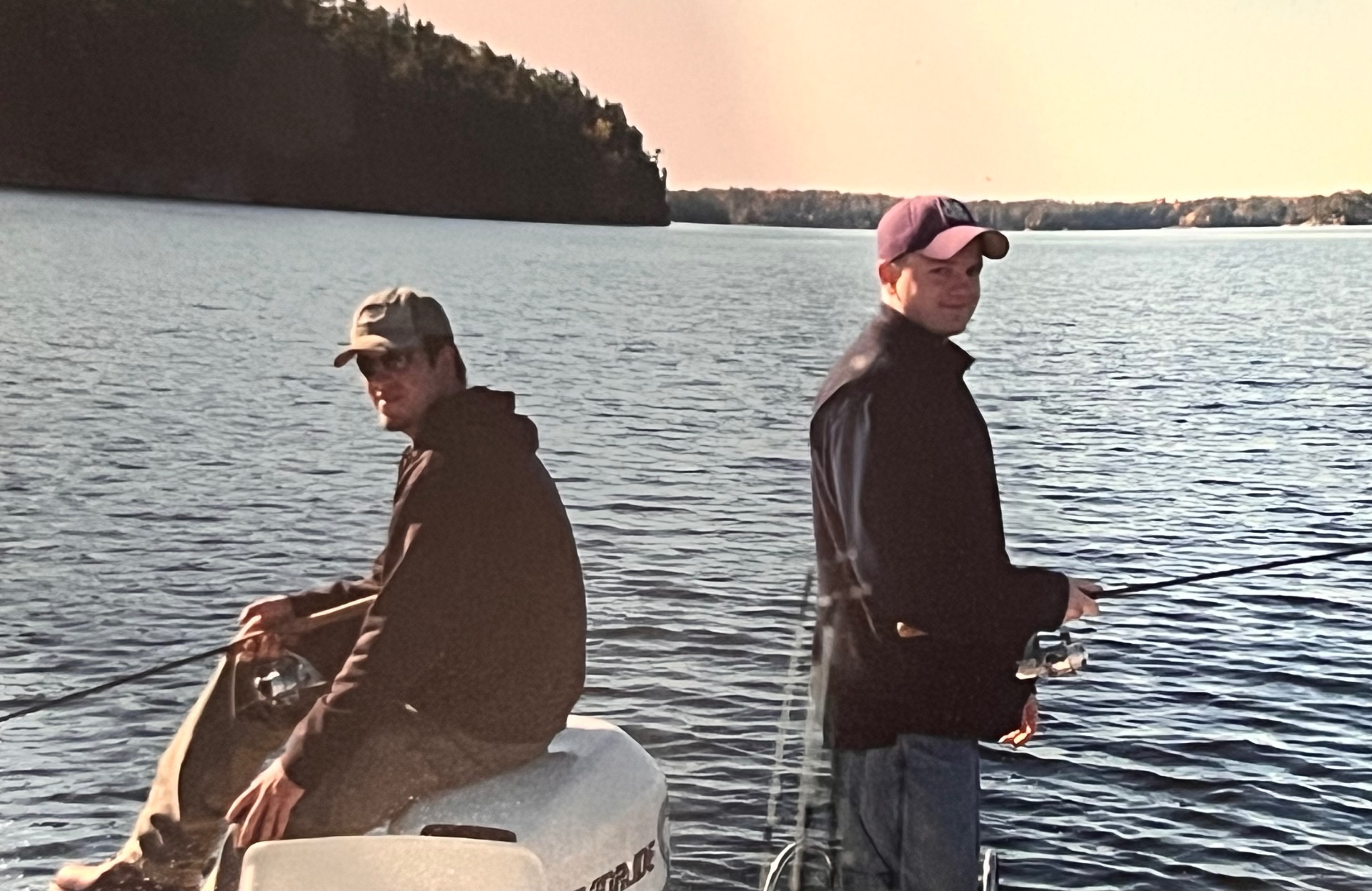Back-to-back on the boat at sunset — quiet lake, quiet company, perfect end to a day of fishing