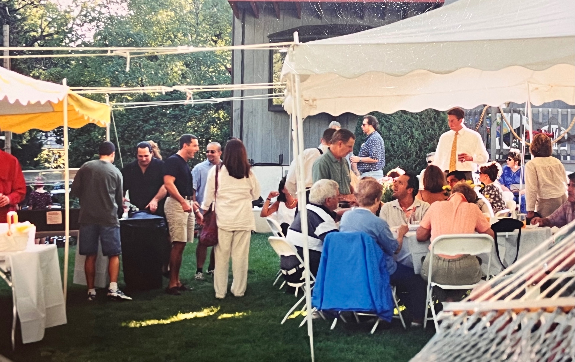 The full yard in full swing — tents up, tables packed, generations mingling on the grass. This is what the bake looked like every year