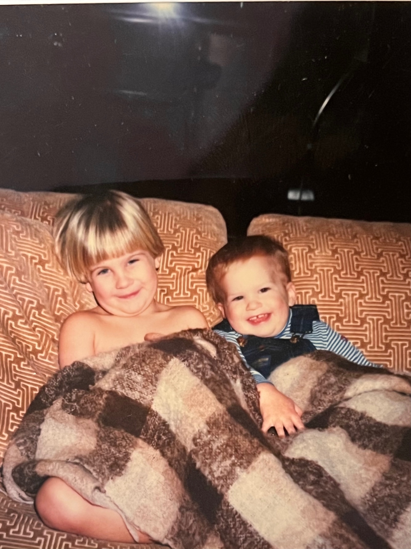 Two little brothers under a blanket — grins that never faded