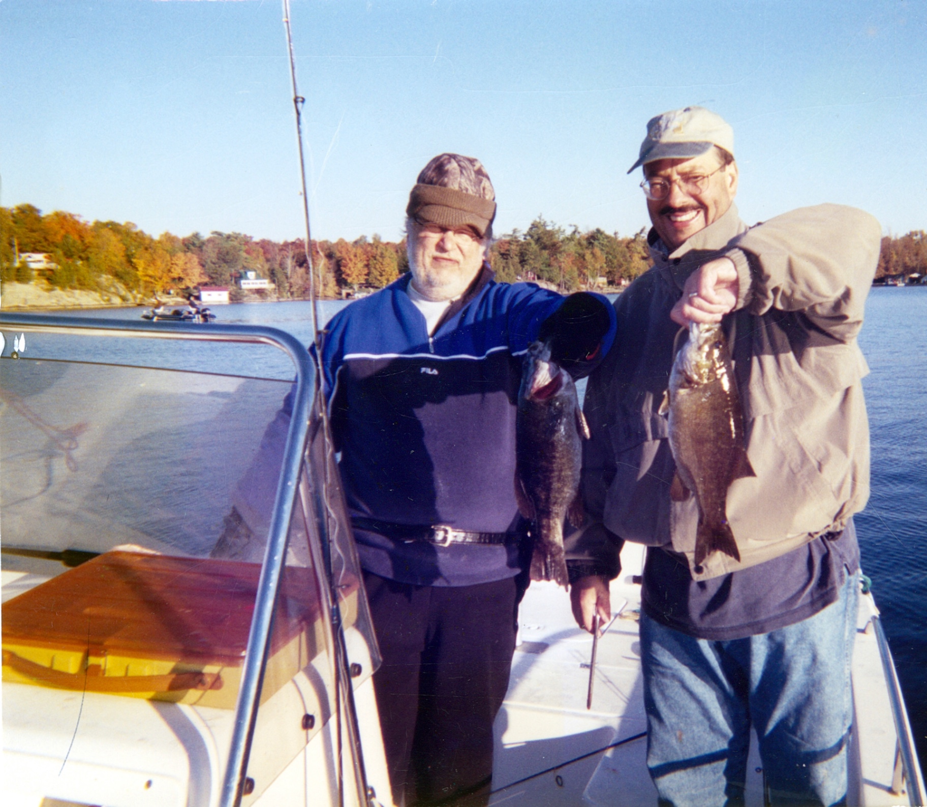 Richard and Bob — best friends, matching grins, matching fish. Fall colors on the shoreline