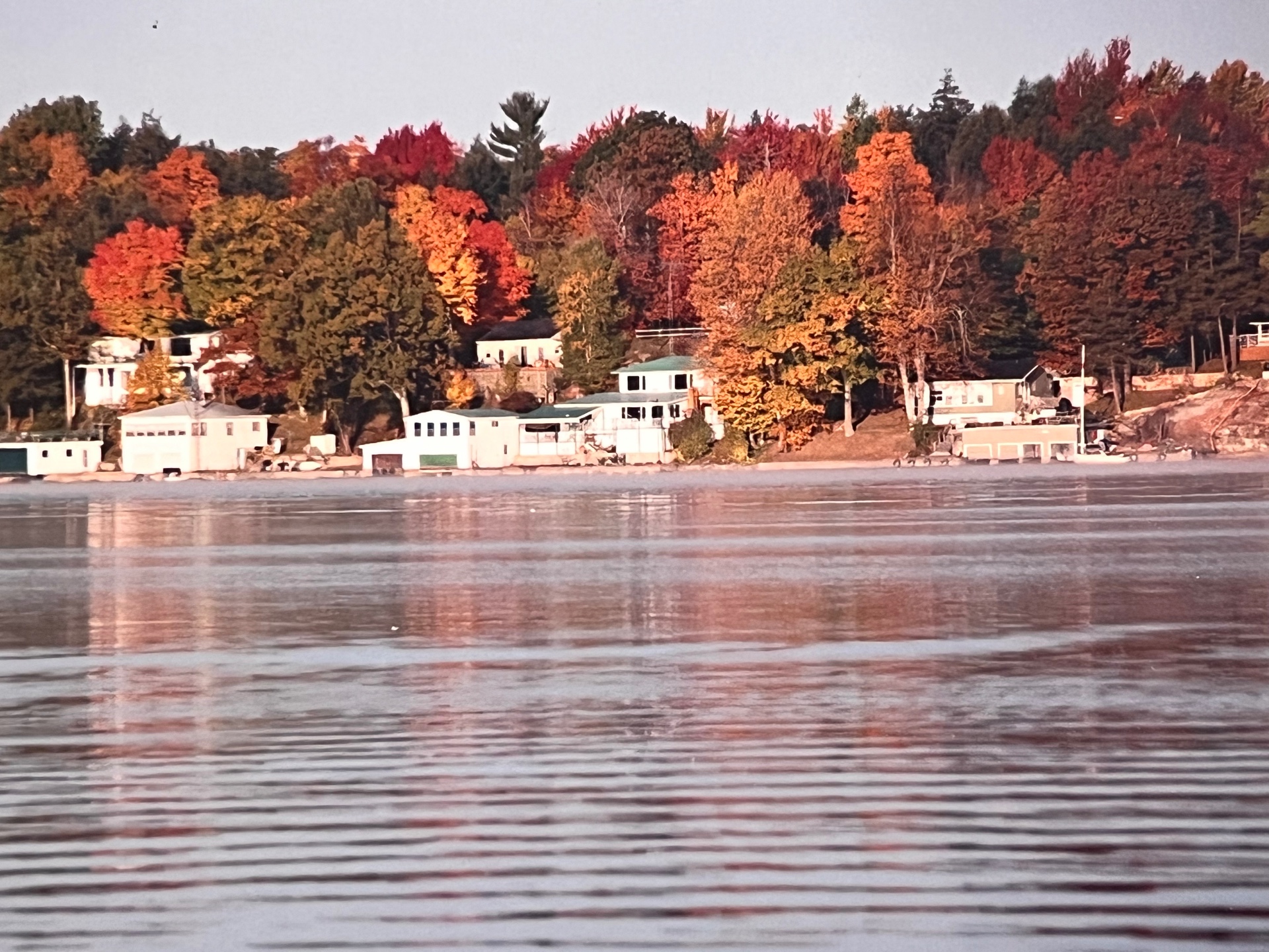 Autumn reflections on the lake — the cottages tucked into a blaze of red and gold along the Canadian shoreline