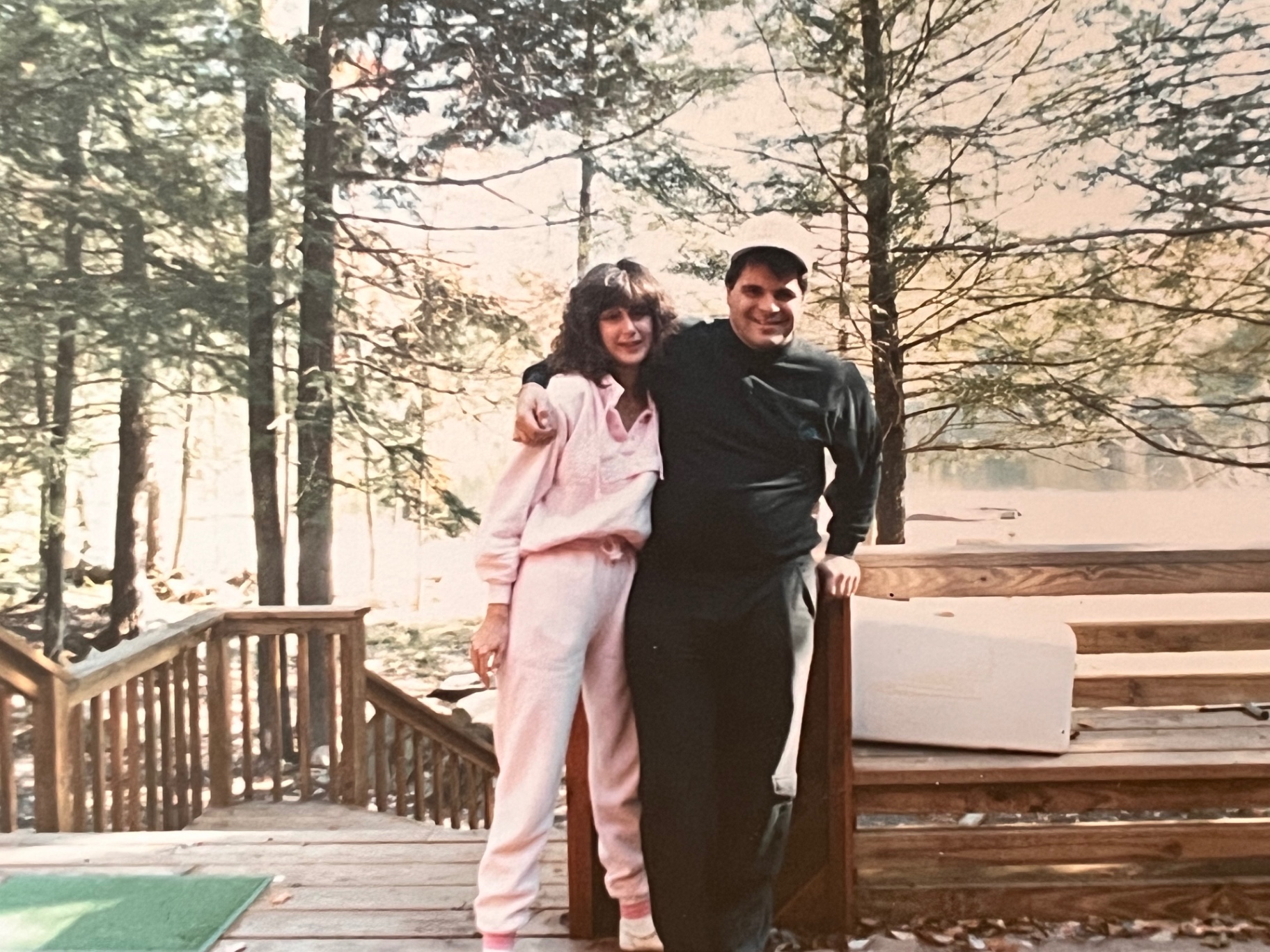 On the cabin deck at the lake — arm around a loved one, woods all around