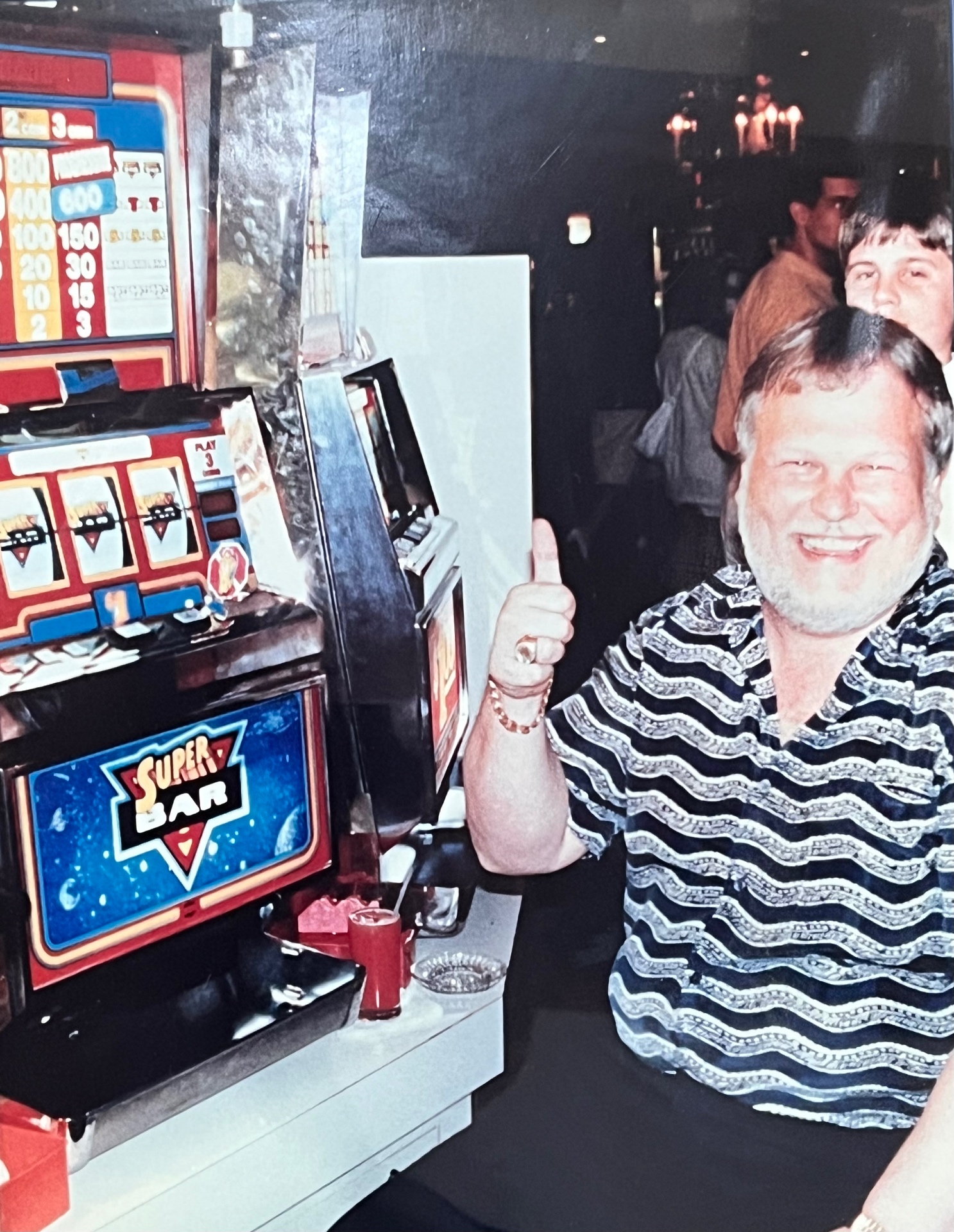 Richard Bladis giving a thumbs up next to a Super Bar slot machine on a Bahamas cruise after hitting the big jackpot