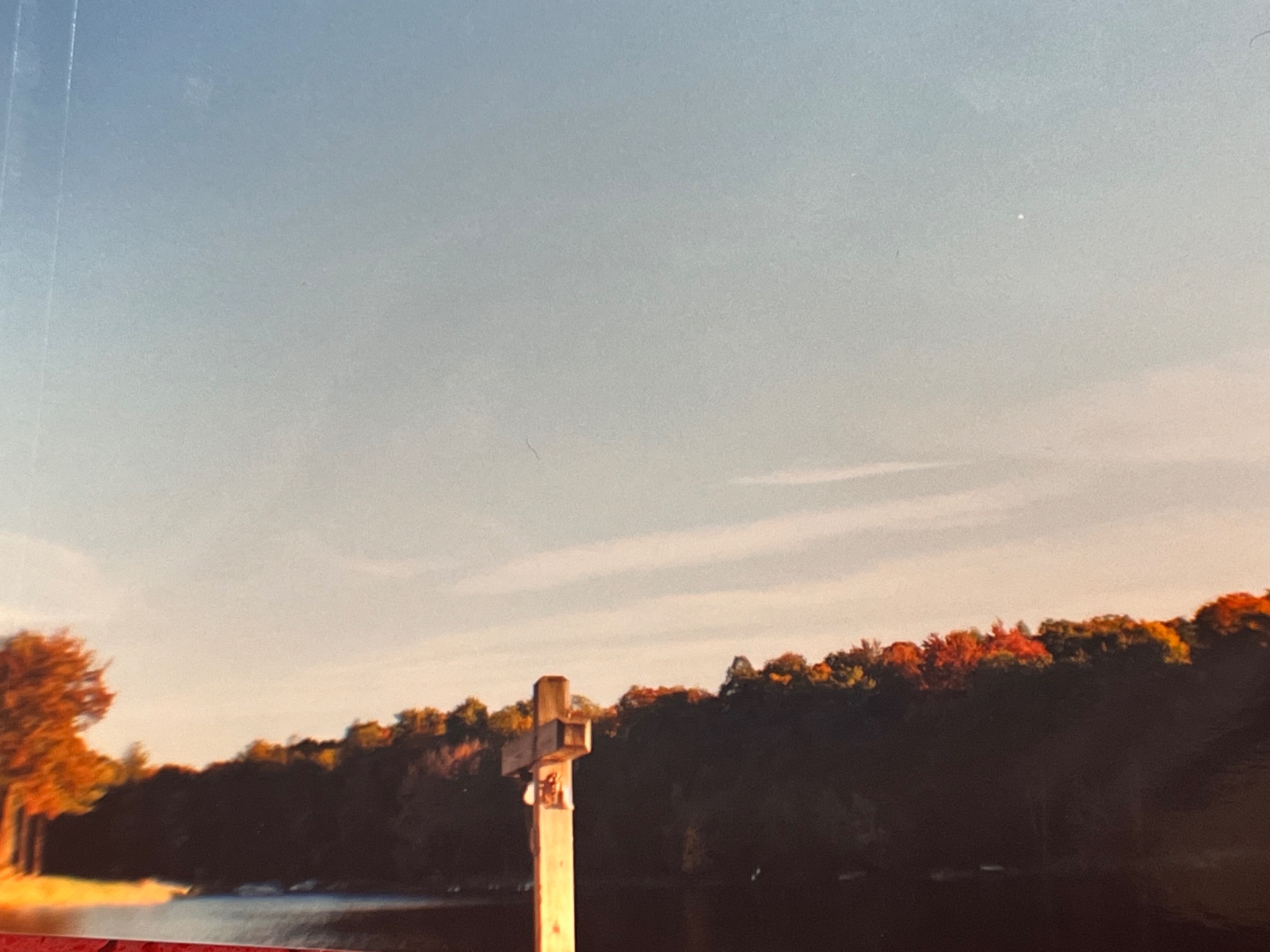 The wooden cross at the dock's edge — dusk falling over the lake at The Hideout