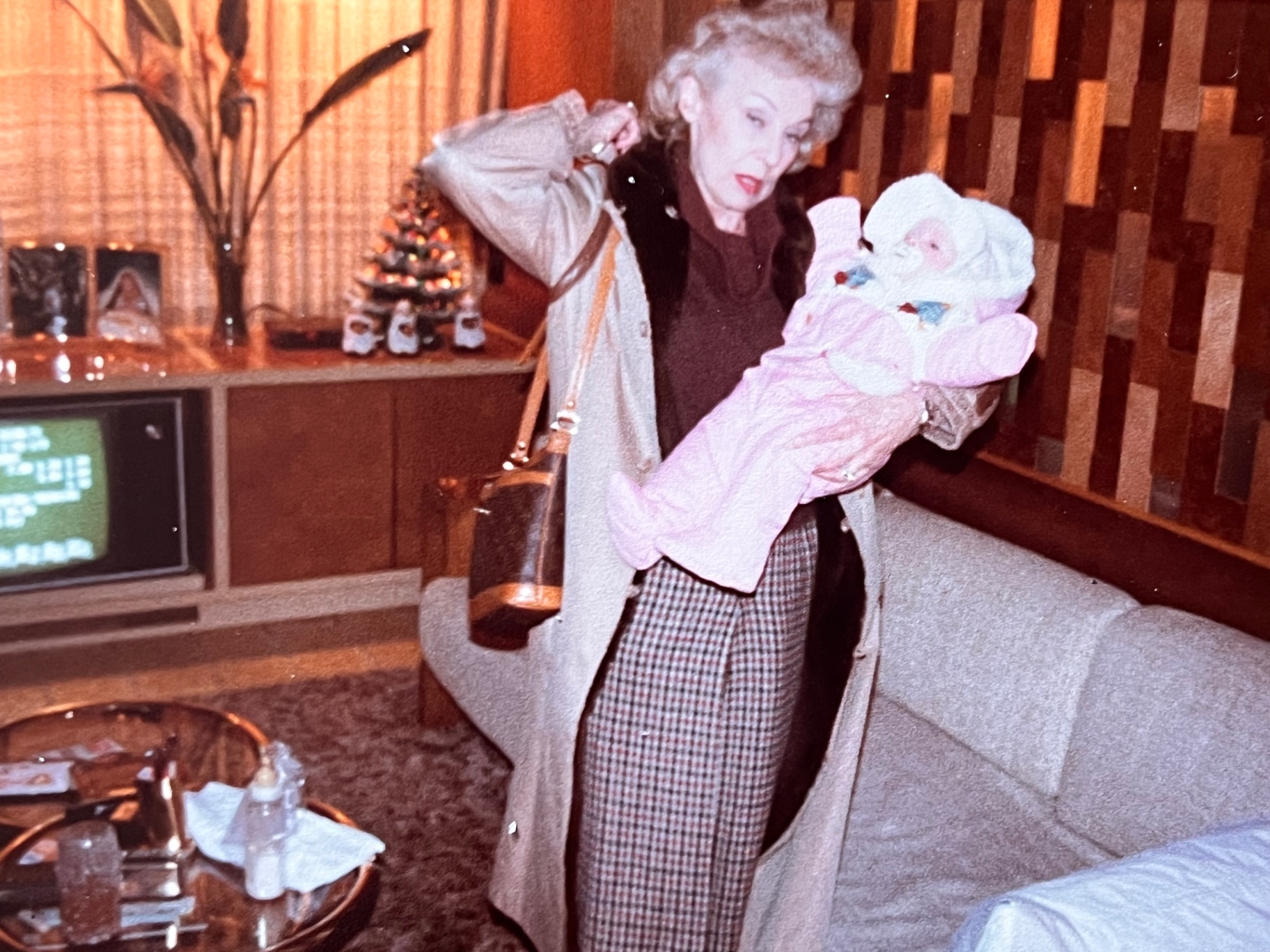 Gloria cradling a tiny grandchild by the Christmas tree — a grandmother's joy