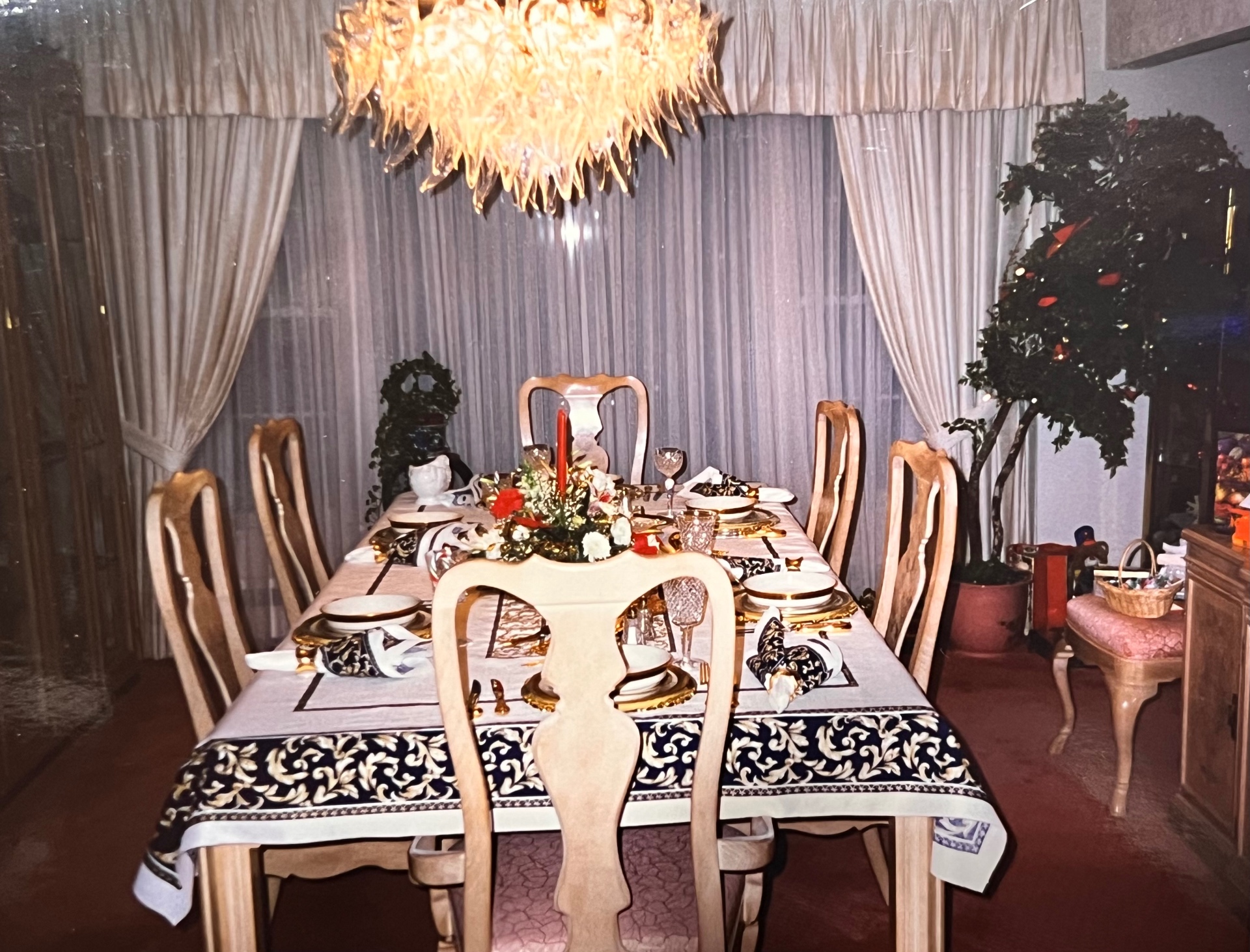 The dining table set for the family — gold chargers, red candle, holly in the corner. Christmas at Grandma's.