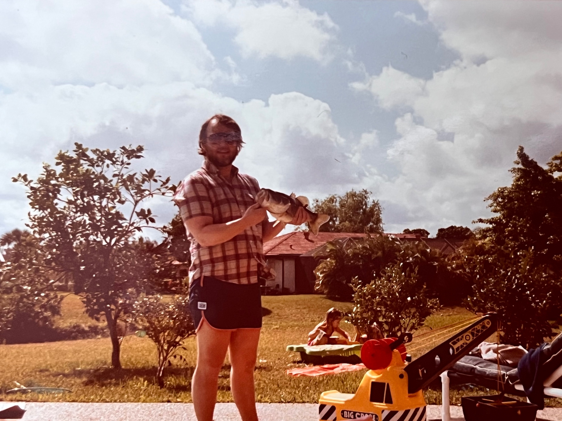 Backyard bass in the Florida sun — the boys playing behind him