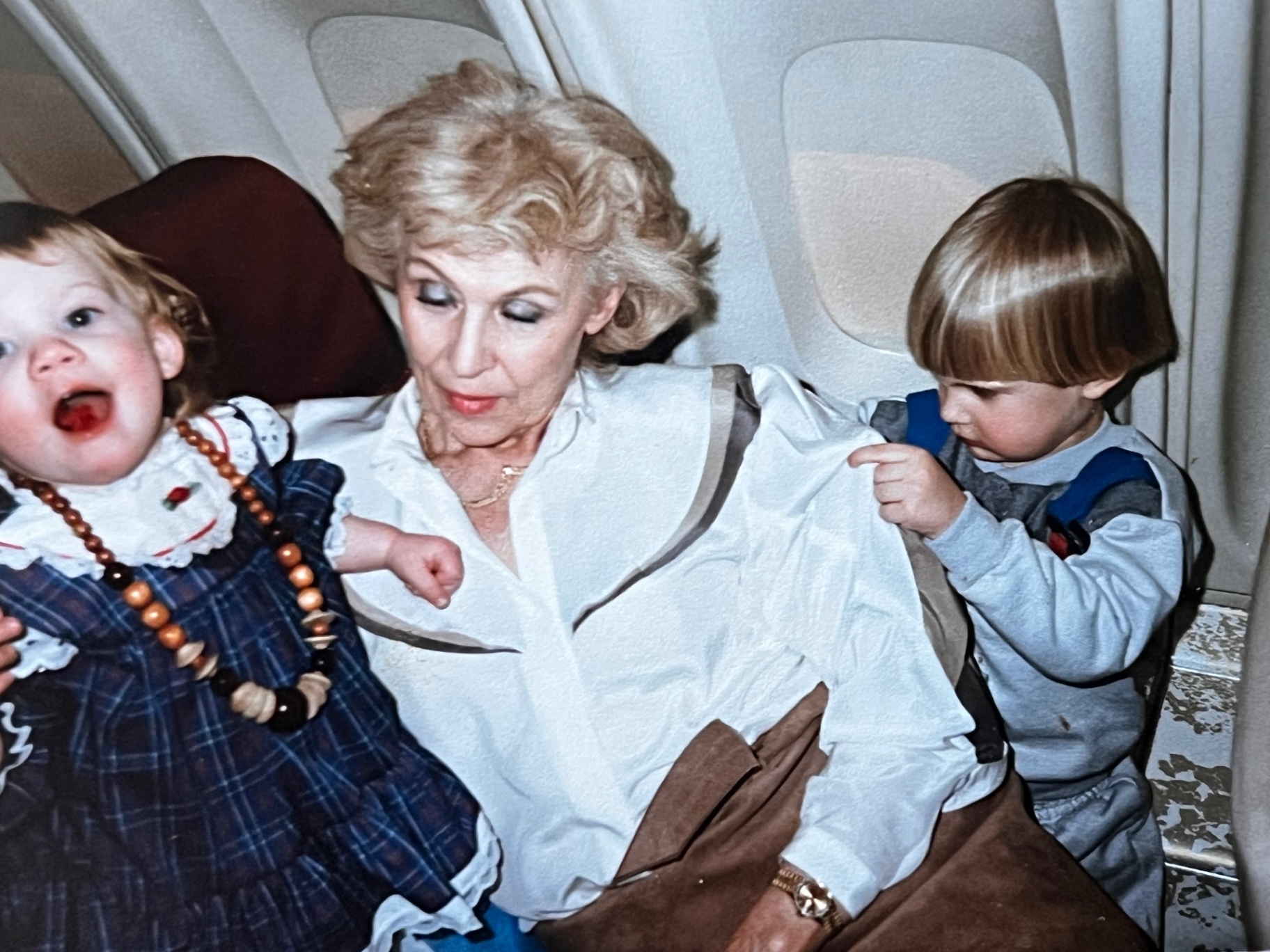 Grandma-in-flight — flanked by two little travelers on the way to somewhere fun