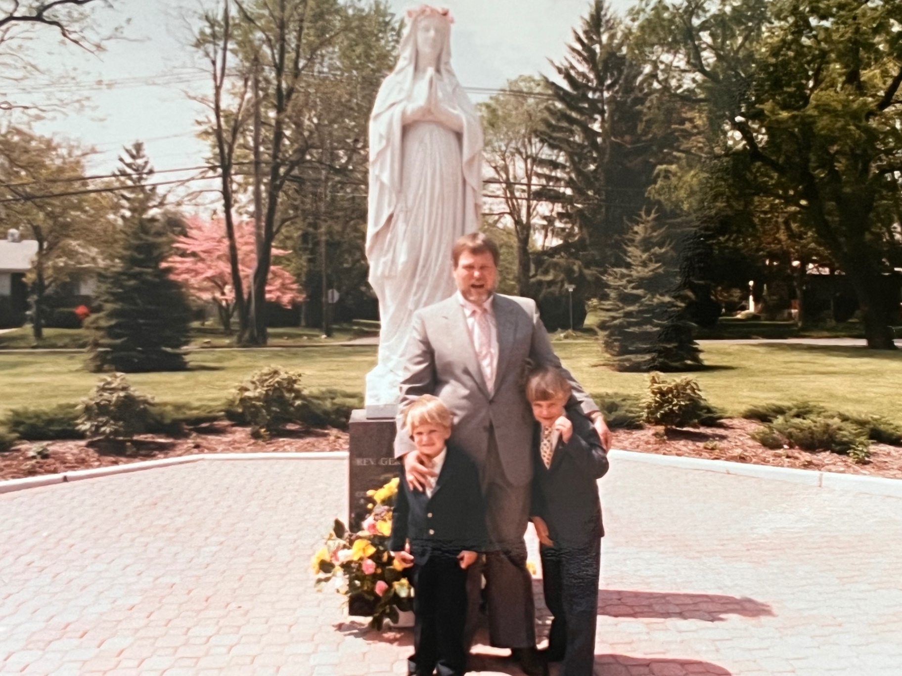 Sunday best with his two boys — suits on, arms around them, faith and family in one frame