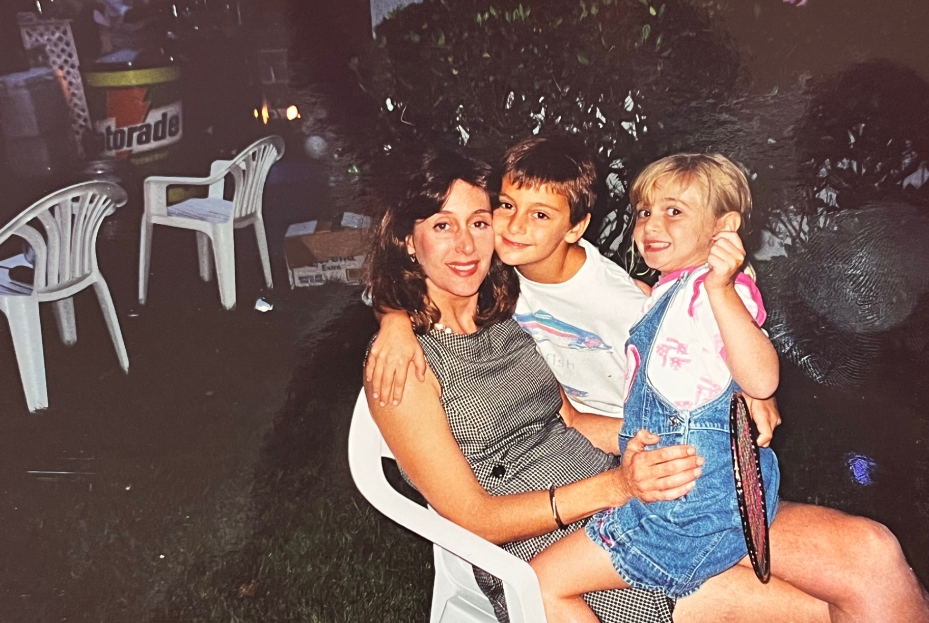 Family in the yard — kids on laps, laughter in the air