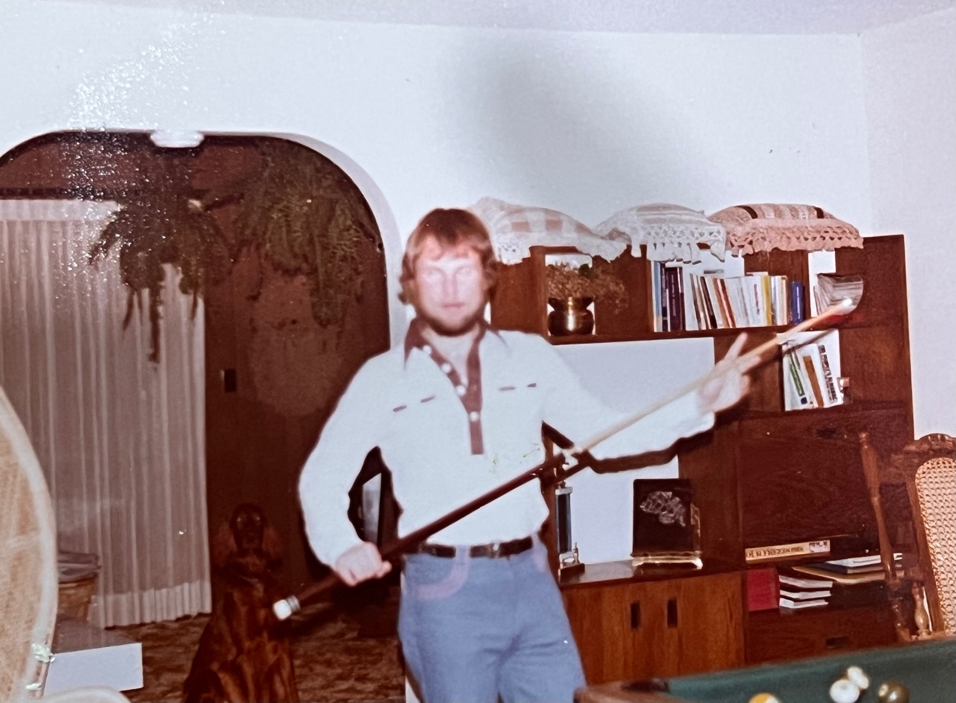 Cue in hand, western shirt on, ready to break — Richard in his den, pool room lit and the table just out of frame