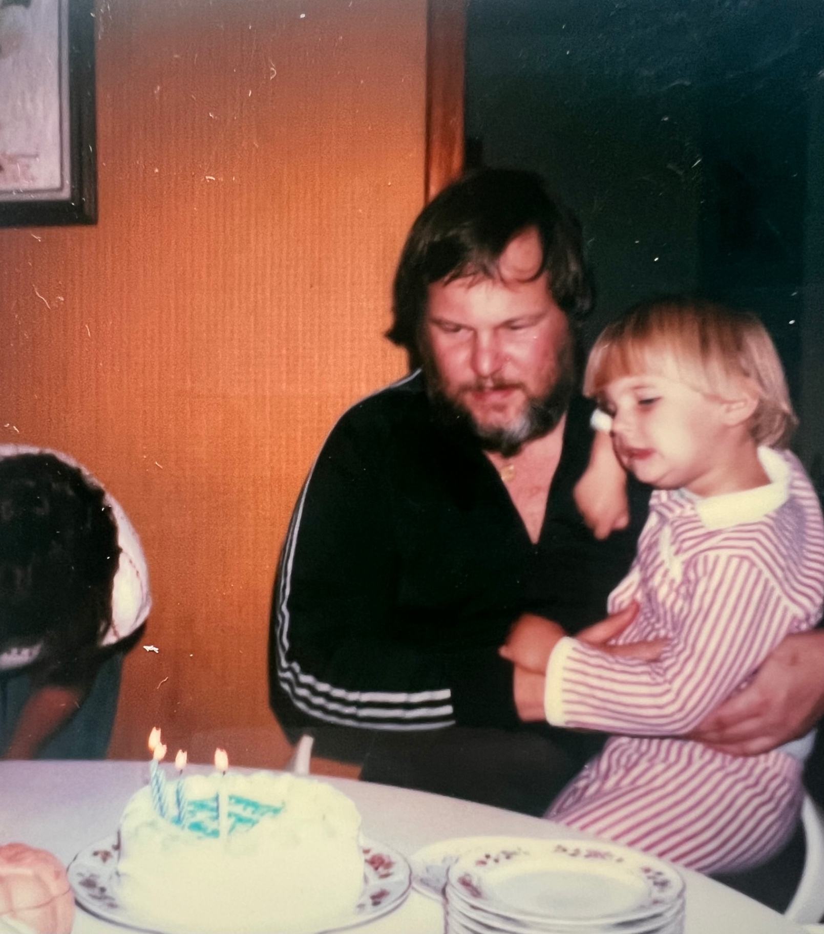 Family birthday, candles lit, the little one on his lap — early days full of love