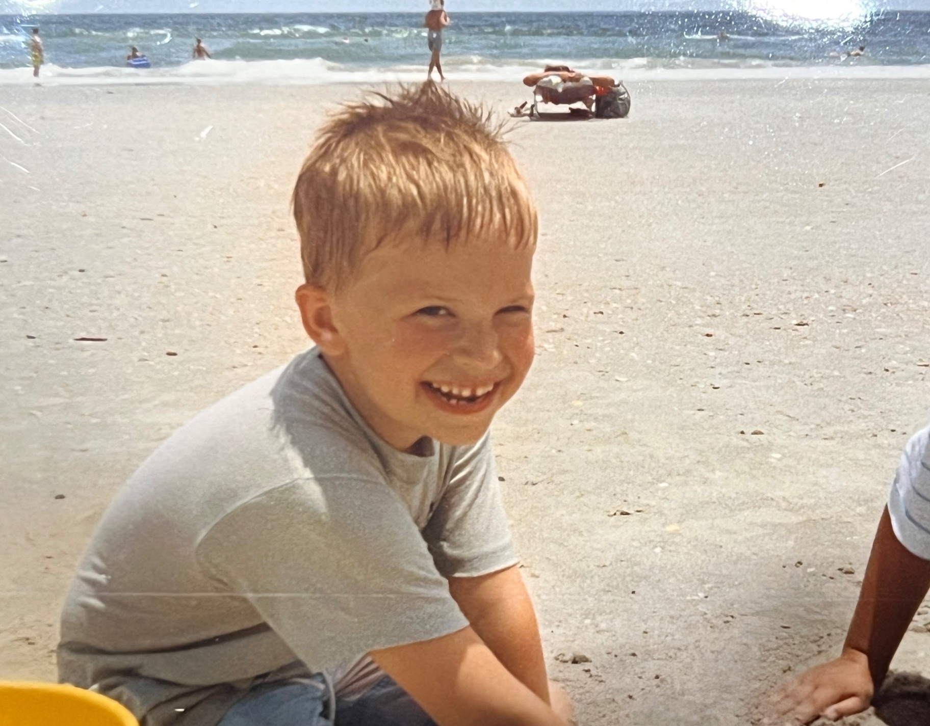 That grin in the sand — a Bladis boy at the shore, exactly where Dad wanted him to be