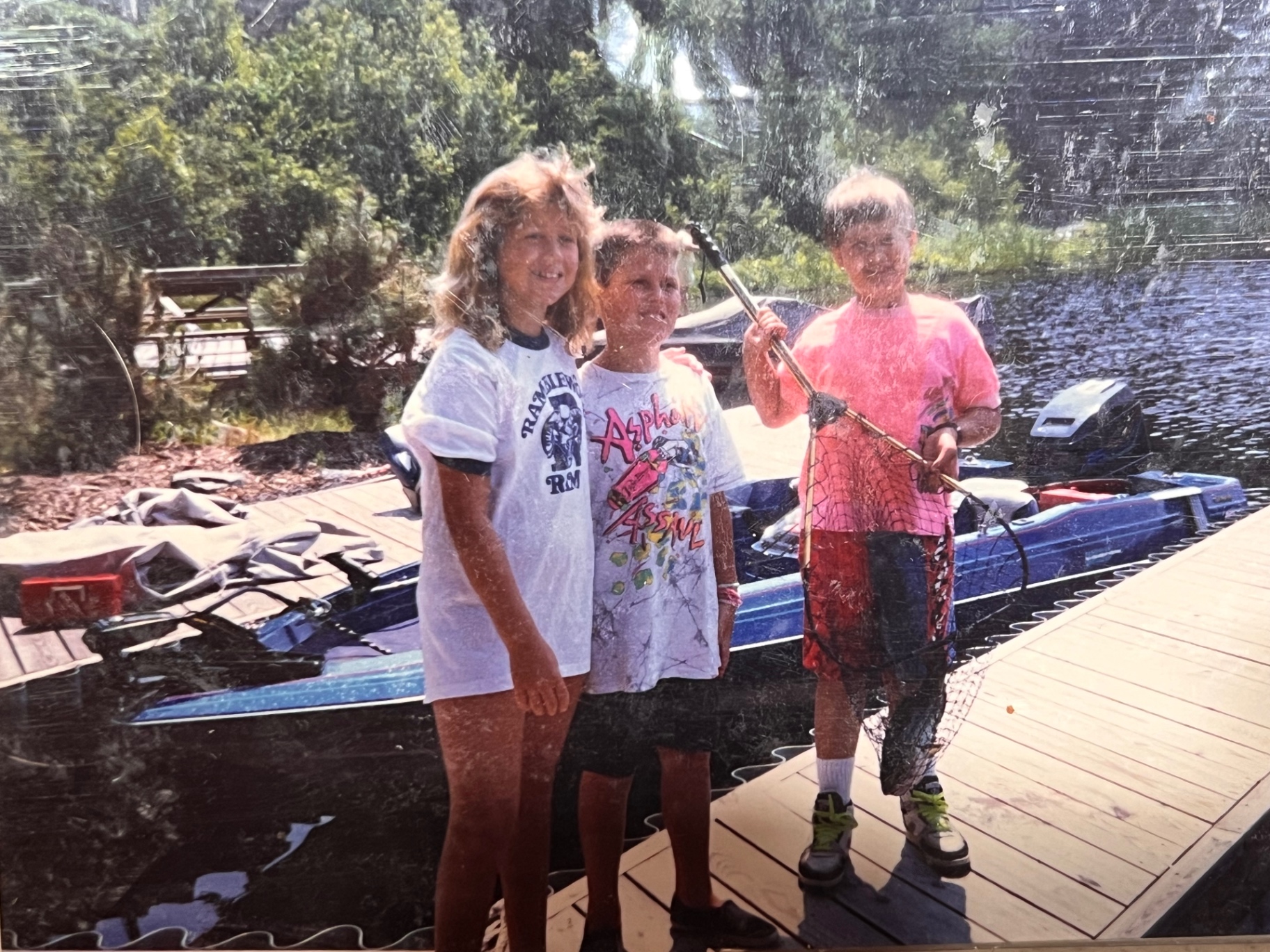 Dockside crew with the fishing net — the boats behind them, the lake in front, everyone smiling