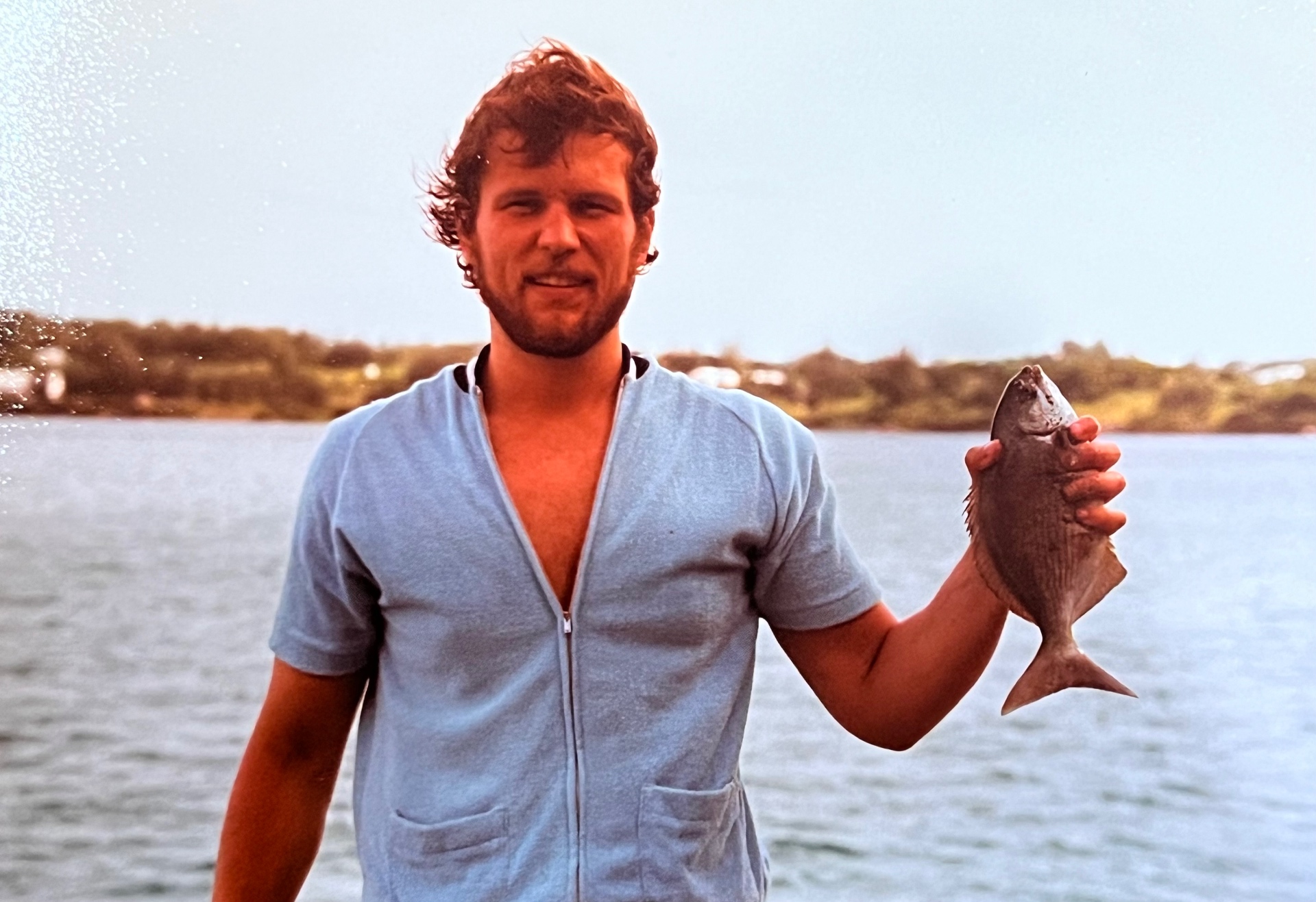 Reef fish in hand off the Bermuda shore — Richard, curls in the salt air, another one for the book