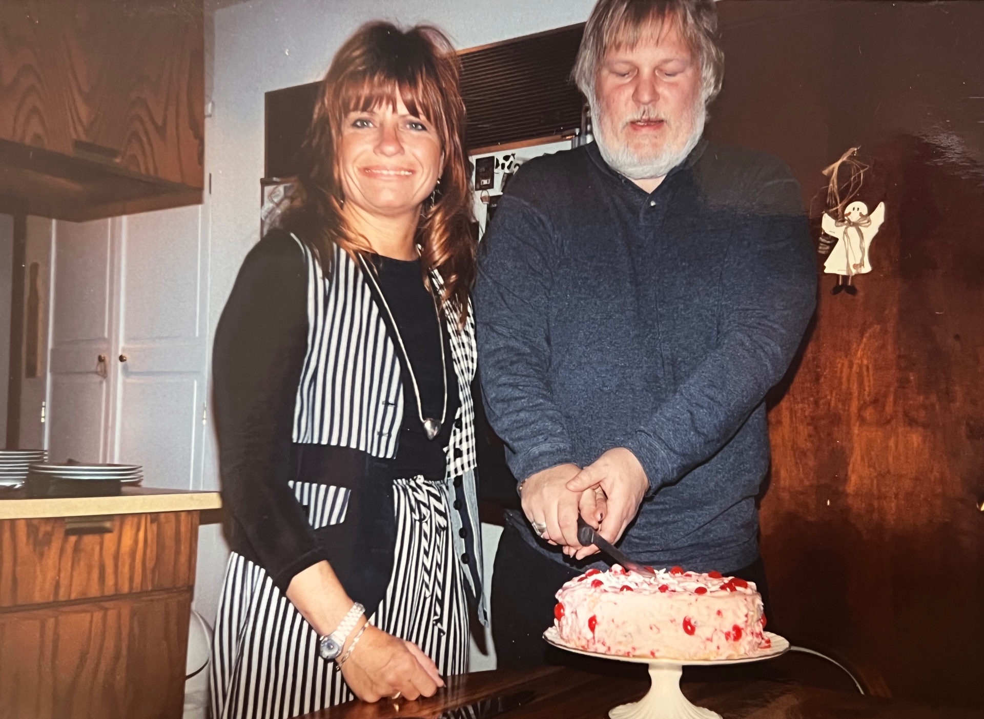 Richard and Yvonne cutting the cherry-topped birthday cake — side by side, hands together, the way they always were