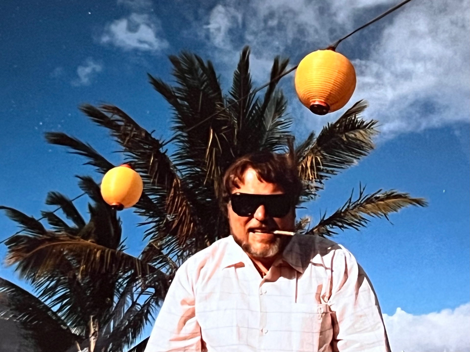 Under the palms — sunglasses on, cigarette lit, not a care in the world