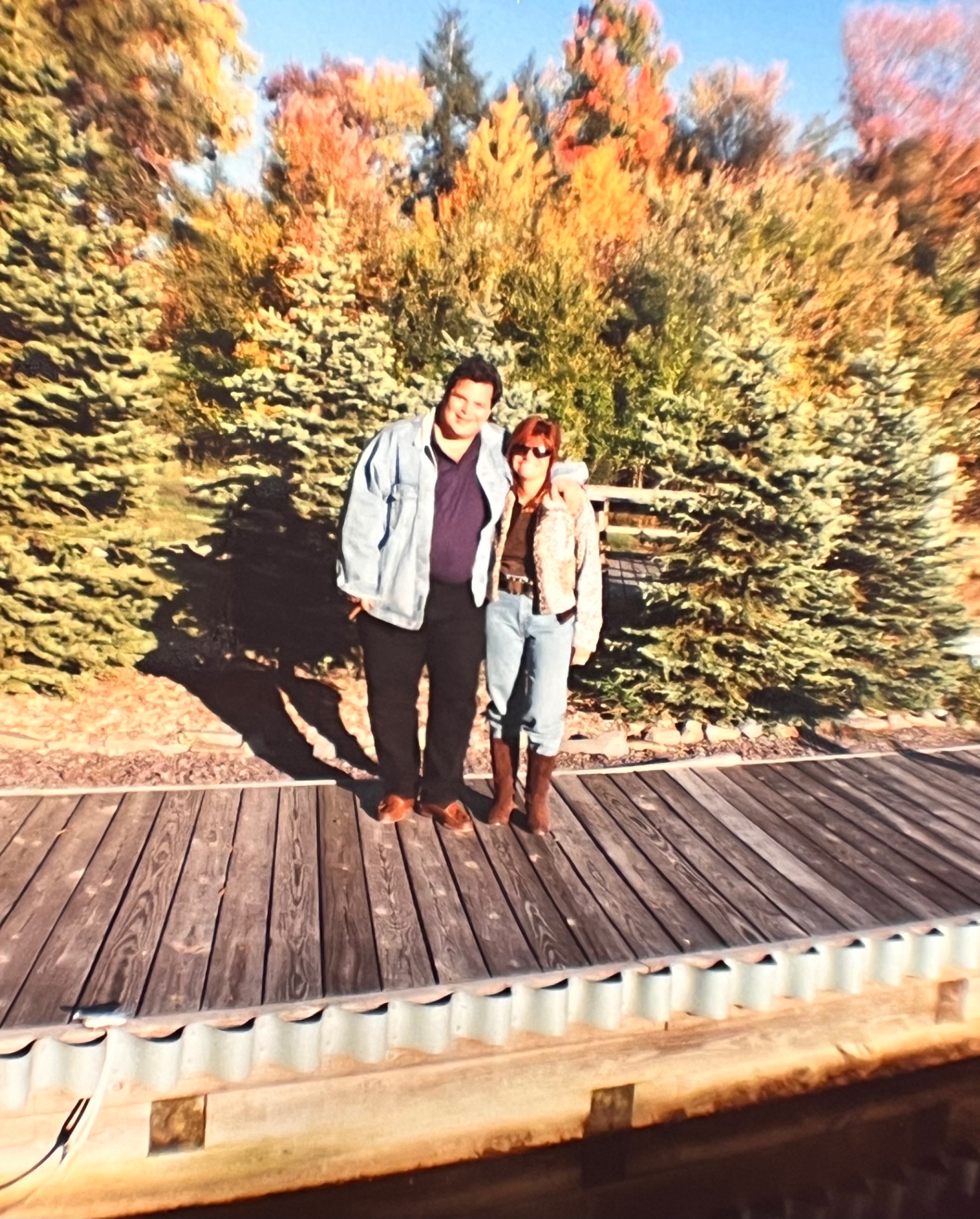 Richard and Yvonne on the Hideout deck — fall colors, evergreens, and the two of them right where they belonged