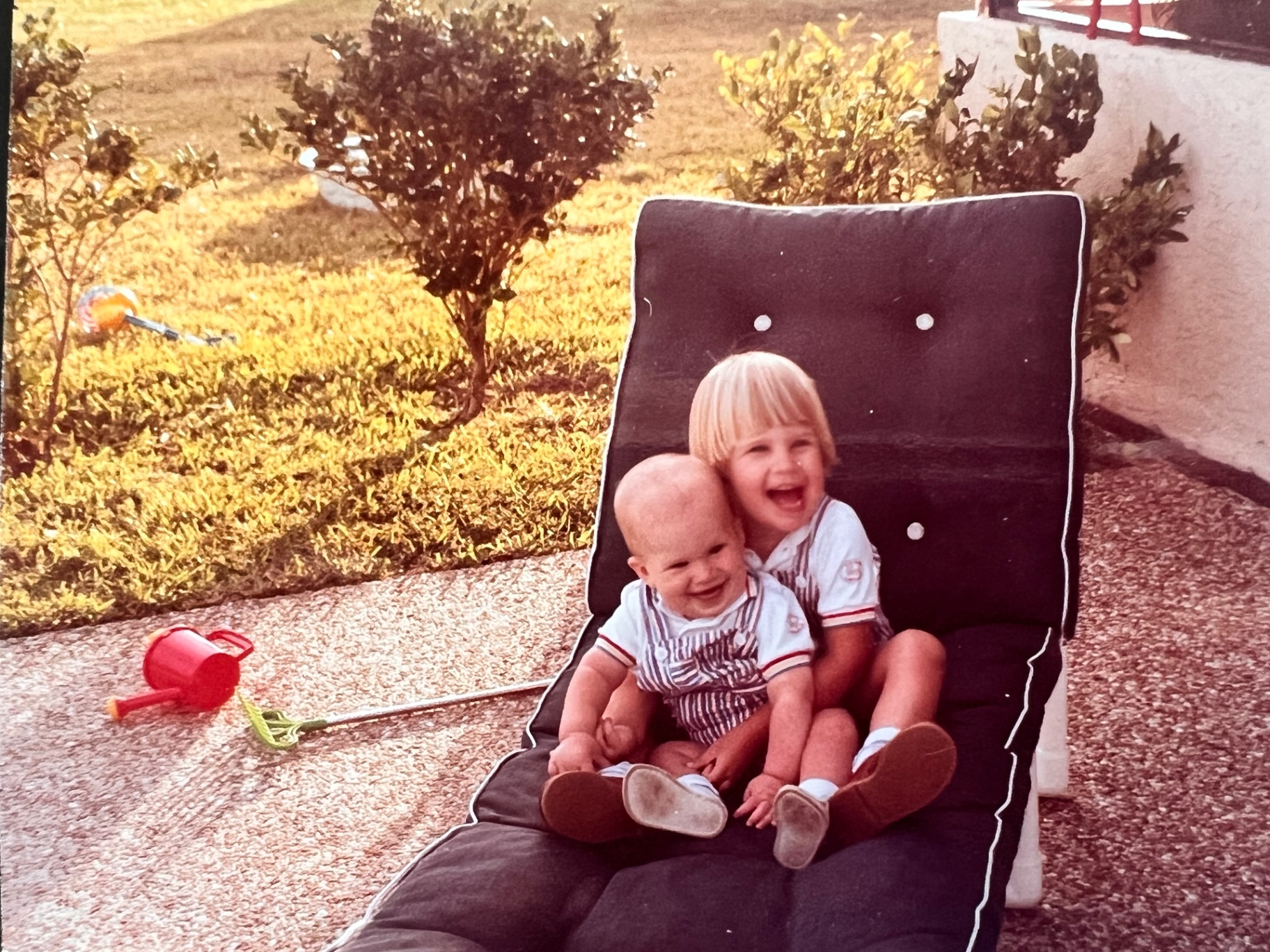 Christopher and baby Jason Bladis laughing together on a garden chair